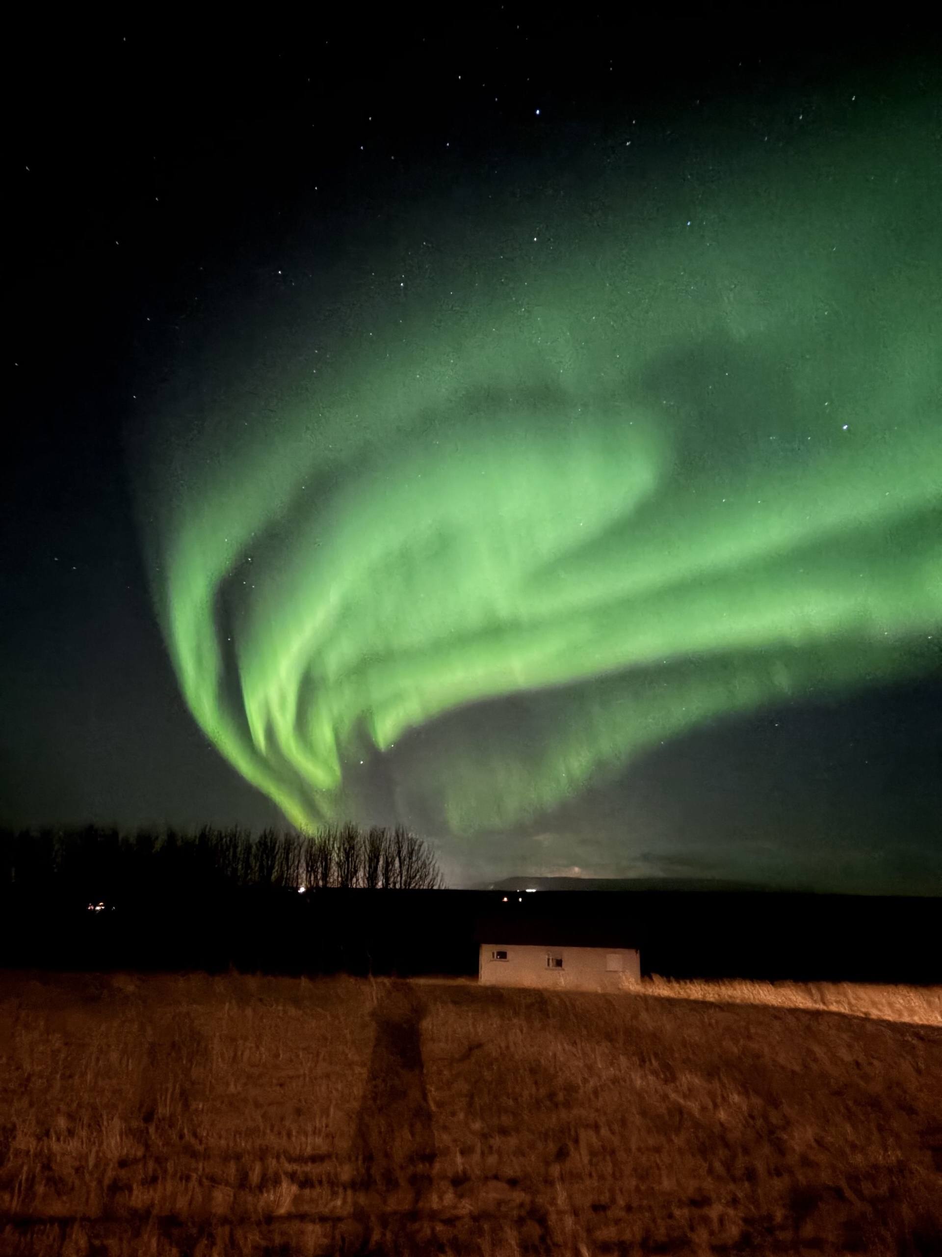 Norðurljós yfir smáhýsi að kvöldi