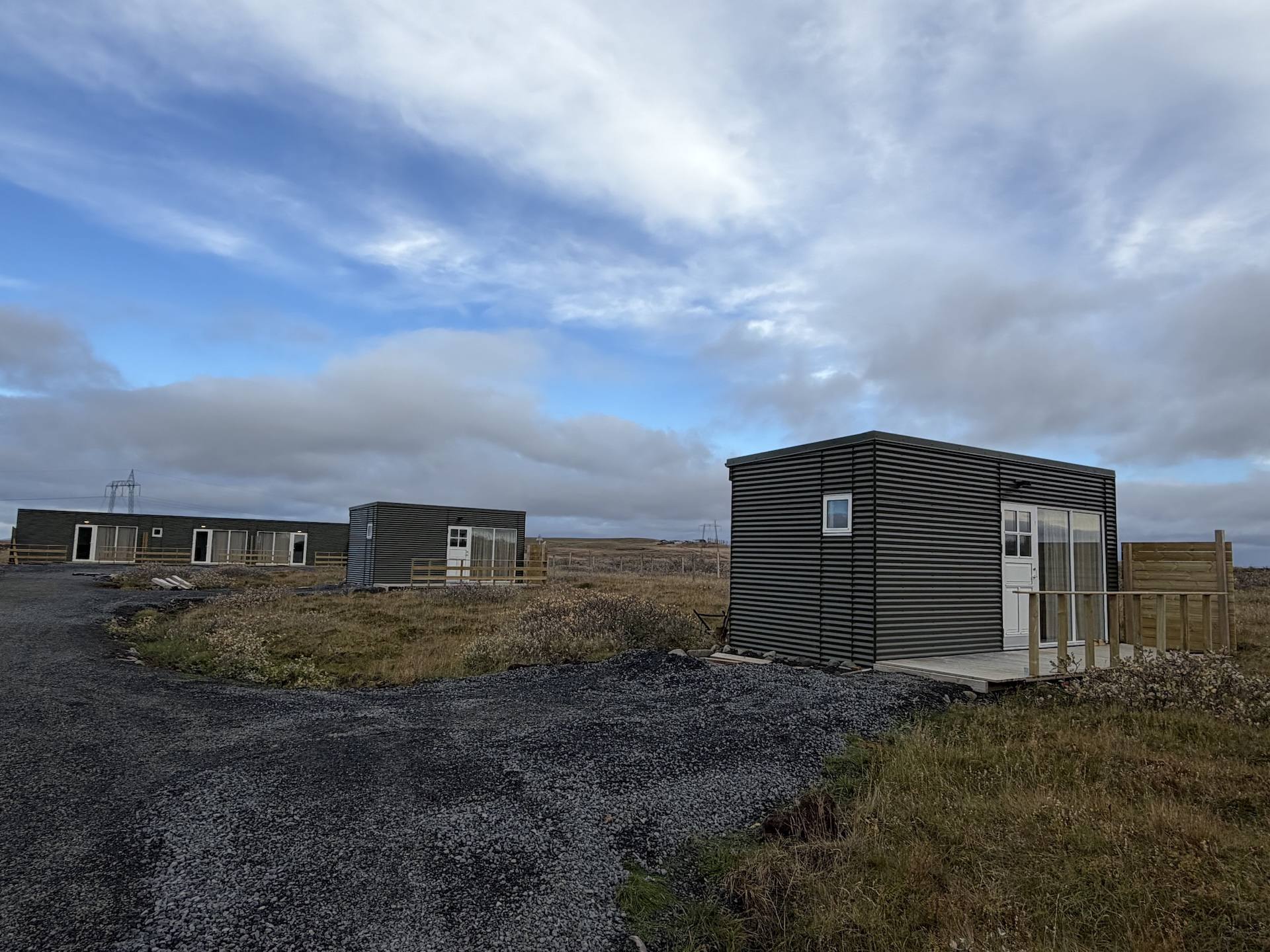 Smáhýsin í Kúrukoti við malarveg undir skýjuðum himni